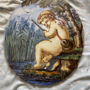 Médaillon ovale céramique polychrome figurant un putto dans les roseaux