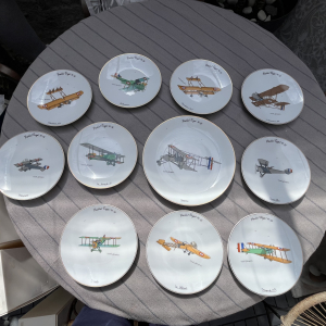 LIMOGES - Marcel Jeanjean Service à dessert en porcelaine série "Les Vieilles Tiges 14-18", illustrations d'aéroplanes comprenant: - 10 assiettes à dessert et un plat à gateau