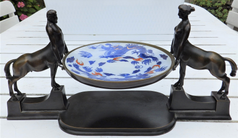 
															Surtout de table en bronze patiné représentant 2 centaures tenant une assiette en porcelaine de Chine - Fin XIXème
														